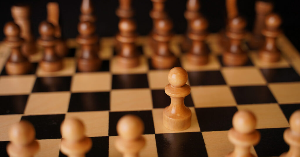 Aerial view of a chess board mid-game with selected pieces illuminated, illustrating sales coverage as a strategic placement decision rather than an organizational chart exercise.